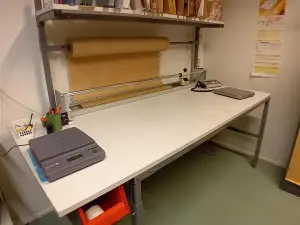 Pakkauspöytä, ylähyllyllä ja pakkauspaperitelineellä